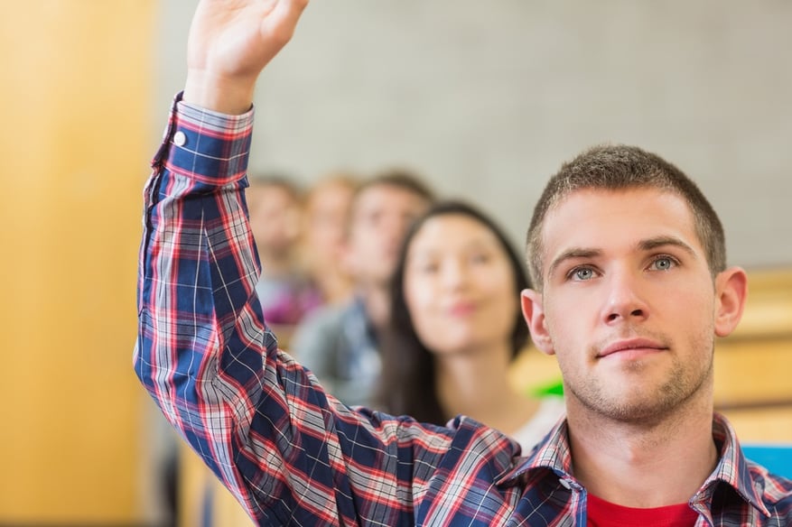 Leading curriculum change amid a changing job market. Close-up of a young male student raising hand by others in a row at the classroom.jpeg